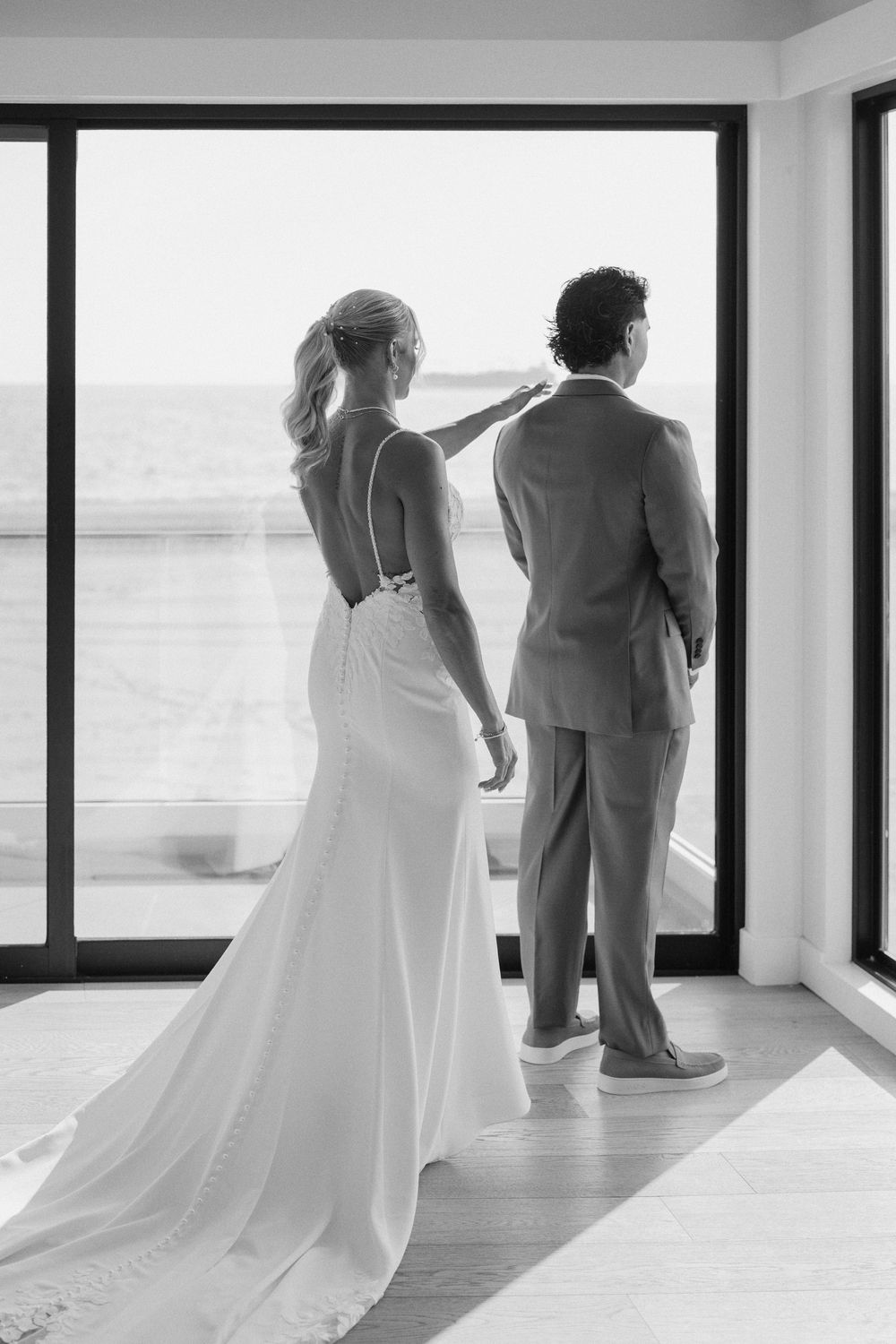A sequence of black and white wedding images showing couples' silhouettes standing by window at a scenic venue during sunset.