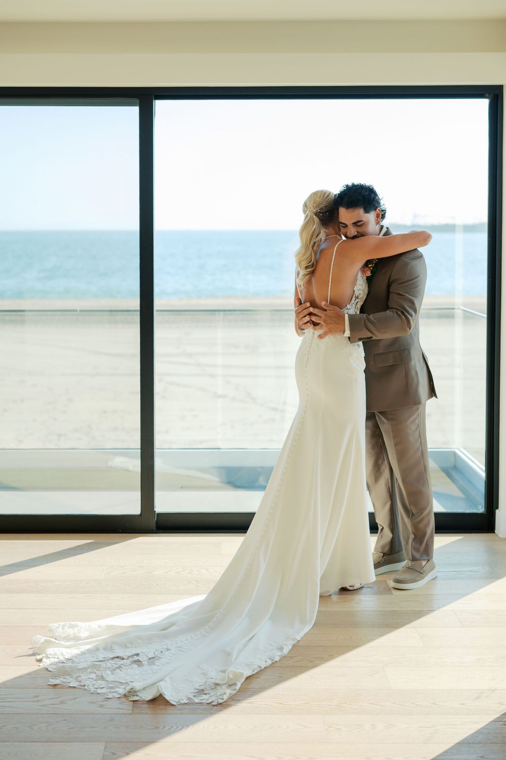 A romantic moment captured between a couple in a sunlit room with large windows overlooking the ocean.