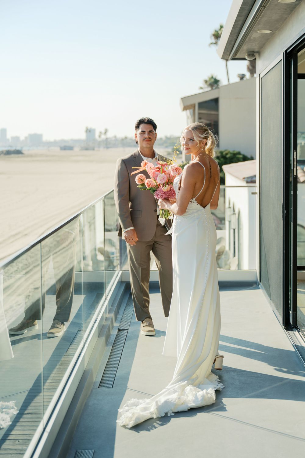 A bride and groom share intimate moments on a modern rooftop terrace with city views in the background.
