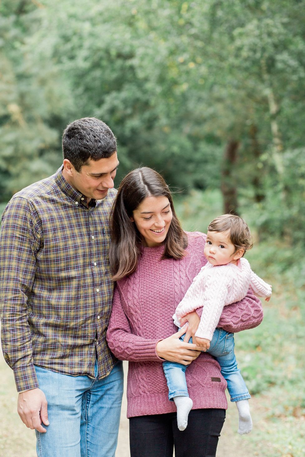 Family wearing pink and plaid share tender moments together in an outdoor autumn setting.
