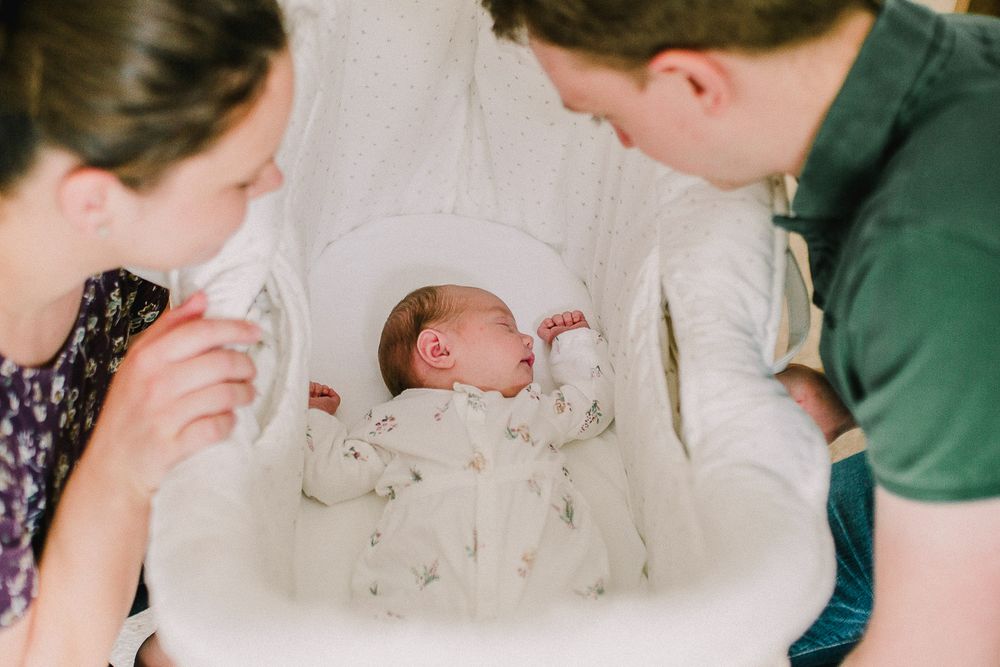 Parents sharing intimate moments with their newborn baby in a bright nursery setting.