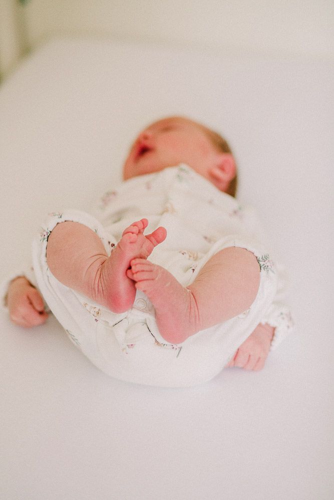 Newborn baby in white clothing lying on white sheets, captured from different angles.
