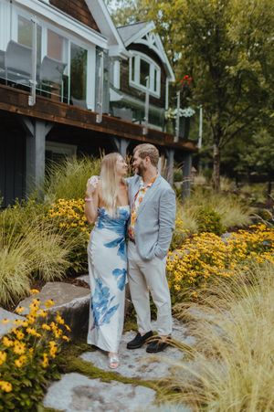 A couple shares a romantic moment in a garden filled with yellow flowers and ornamental grasses.