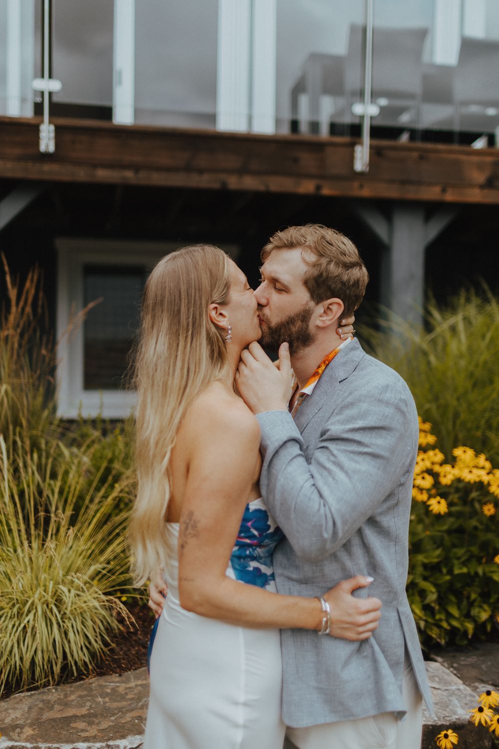 An intimate moment between a couple surrounded by yellow flowers and natural landscaping.