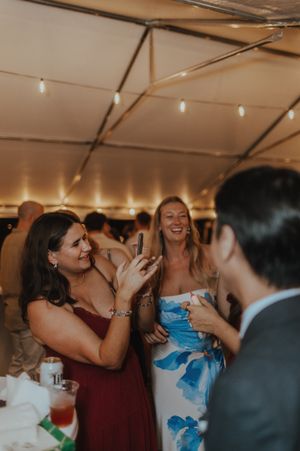 Wedding guests share laughter and joy during an indoor reception under warm lighting.