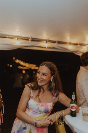 A guest enjoys the evening celebration under string lights at a wedding reception.