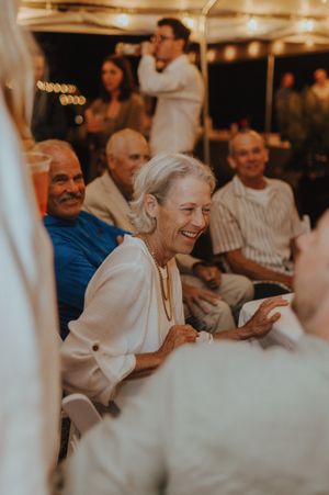 People seated indoors sharing joyful laughter during a social gathering.