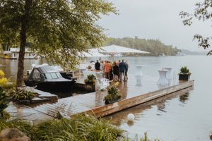 Waterfront wedding venue with white tents and boats visible in the background on a cloudy day.