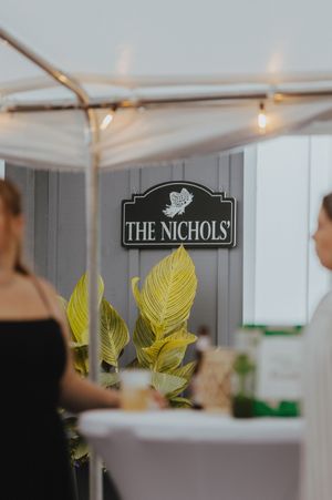 Wedding reception tent interior with 'The Nichols' signage and decorative yellow leaf accents.
