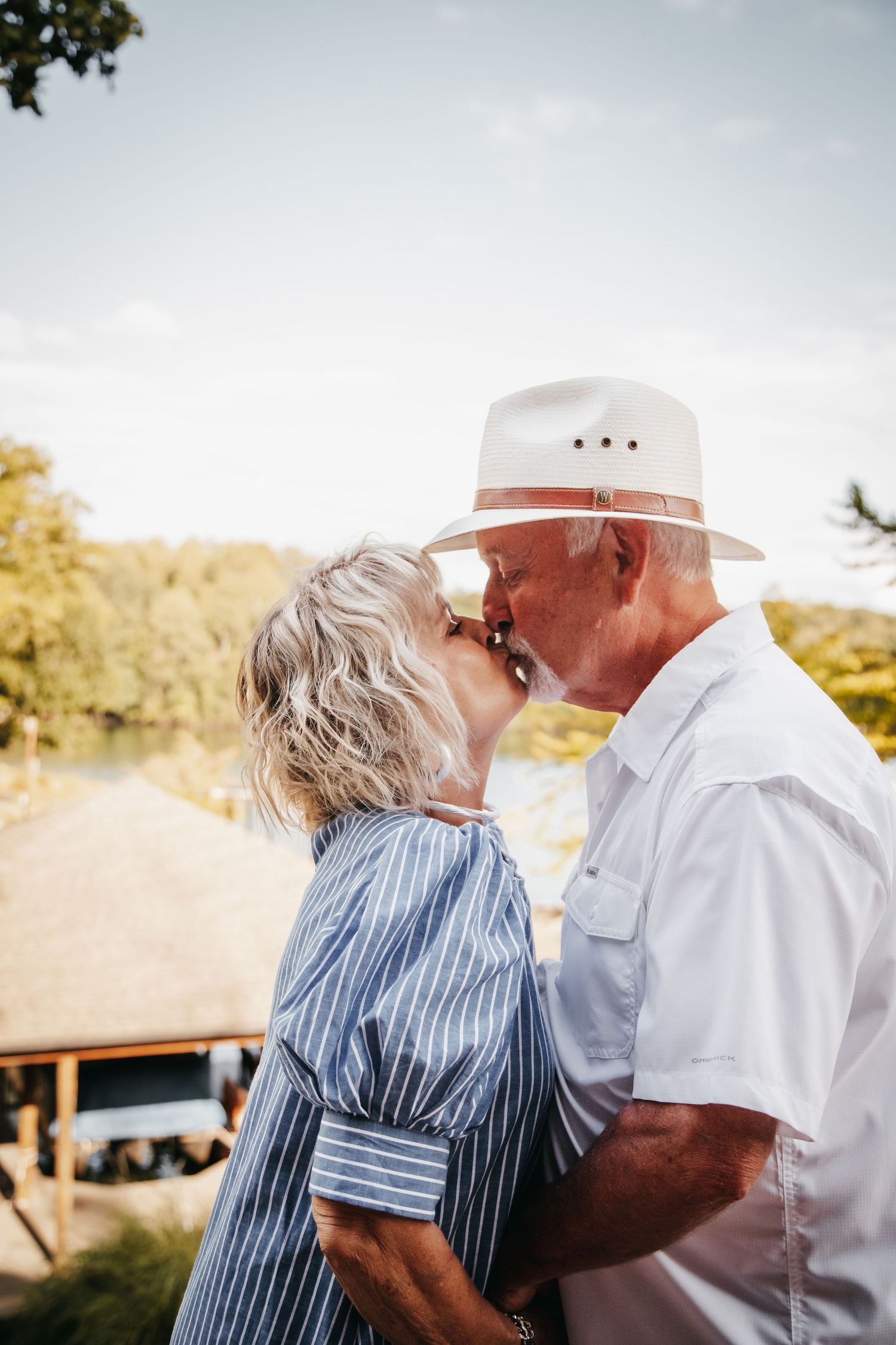 A husband and wife share a kiss by Smith Mountain Lake.