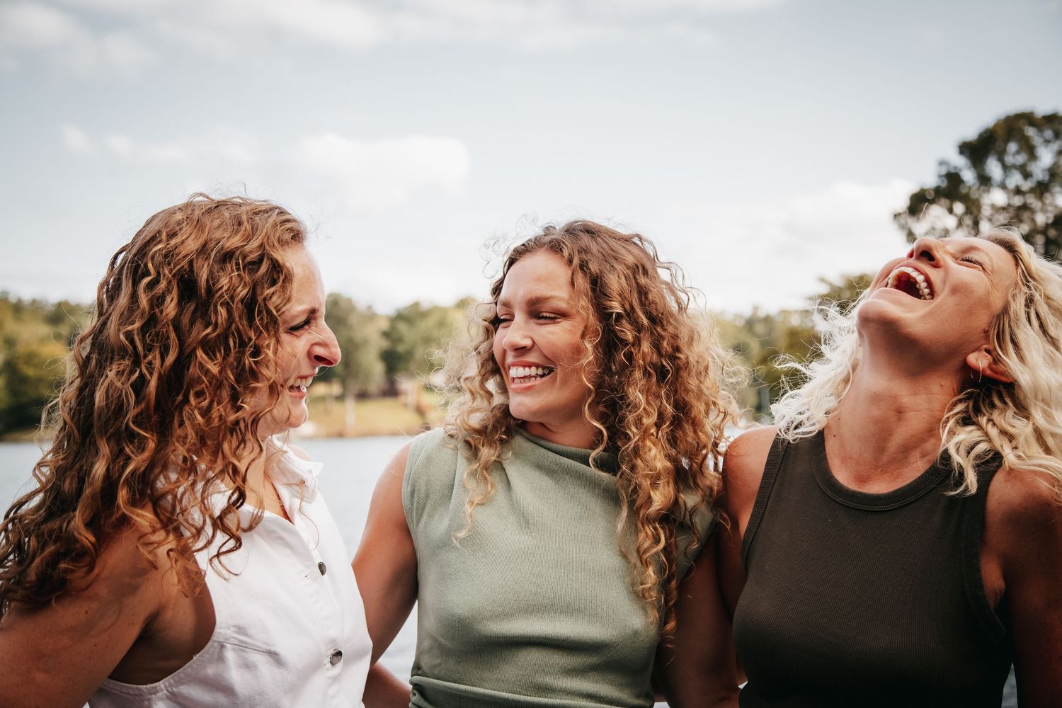 Three sisters laughing and embracing.