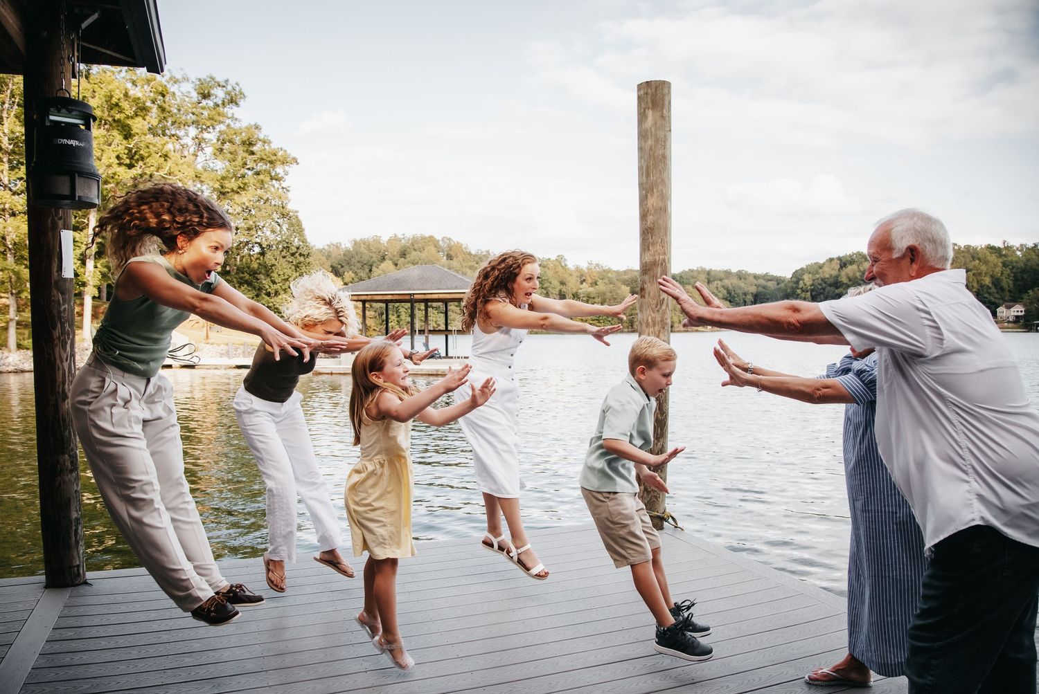 Smith Mountain Lake family jumps on dock overlooking the lake.