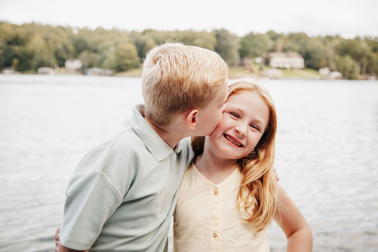 A brother kisses his sister on the cheek overlooking Smith Mountain Lake, Virginia.