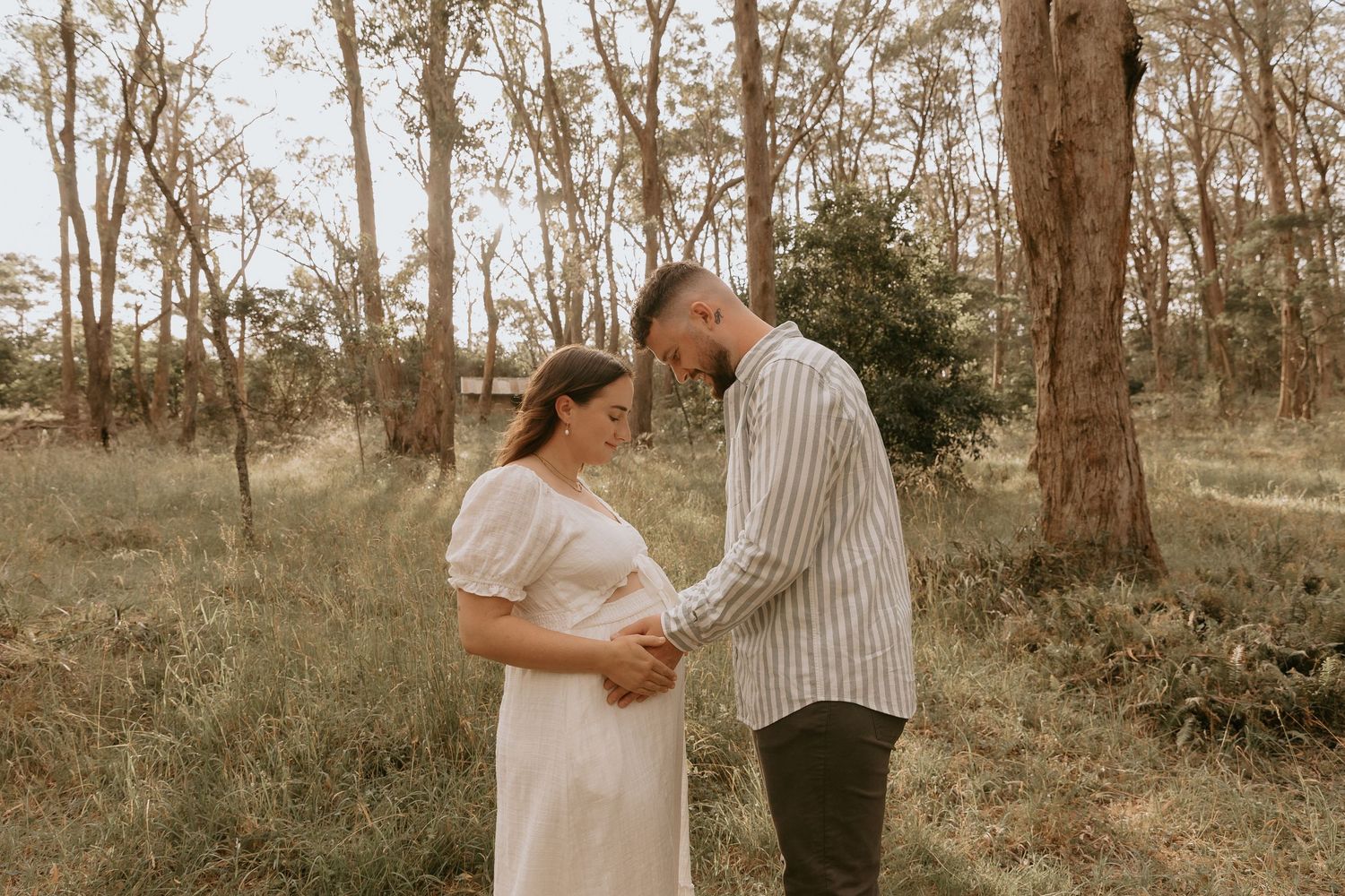 Couple in a romantic outdoor engagement photoshoot among autumn trees in a forest setting.