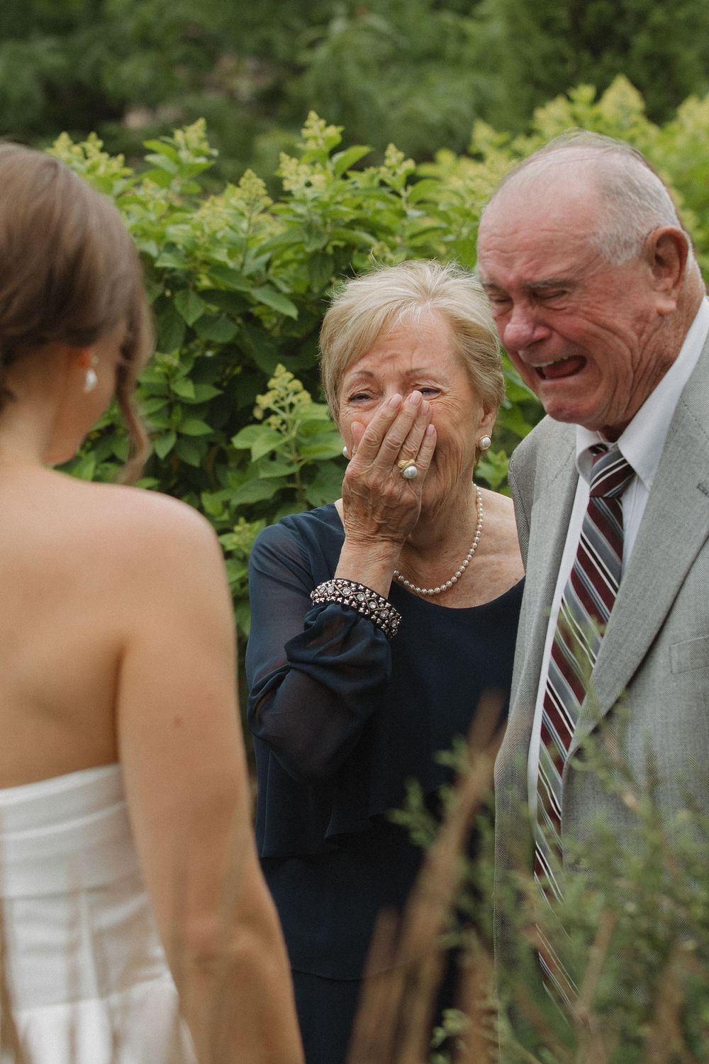 Emotional candid moment captured during outdoor wedding celebration in garden setting.