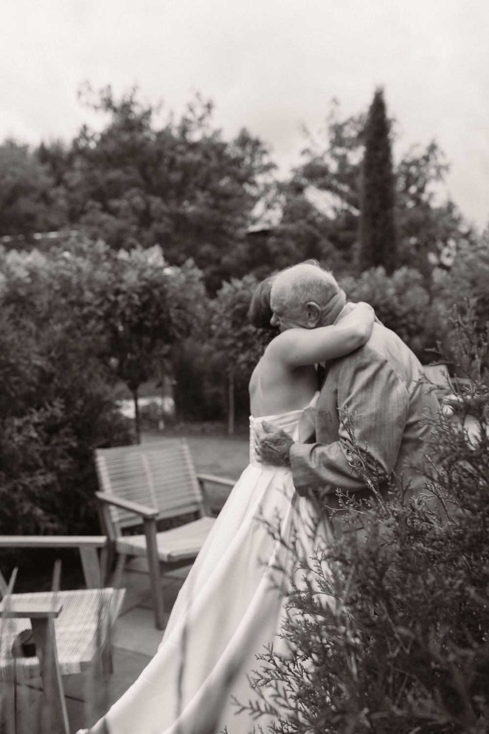 Black and white photo capturing intimate moments between wedding guests in garden setting.