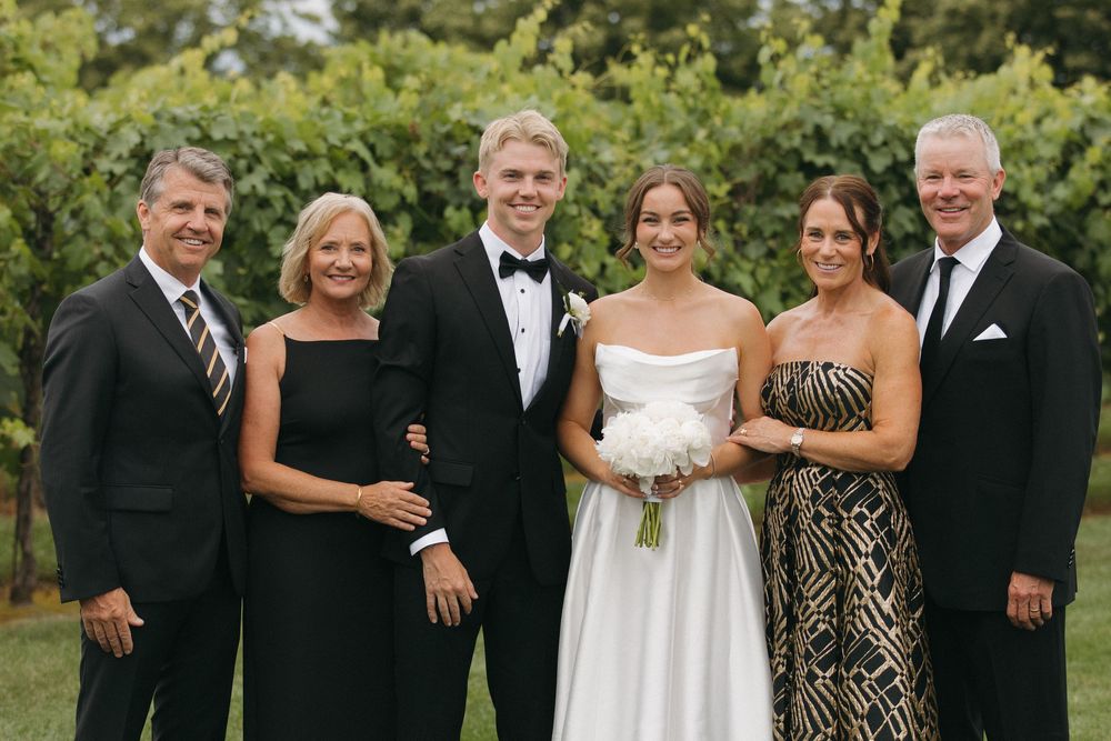 Formal group photo of wedding party members dressed in black and white attire.