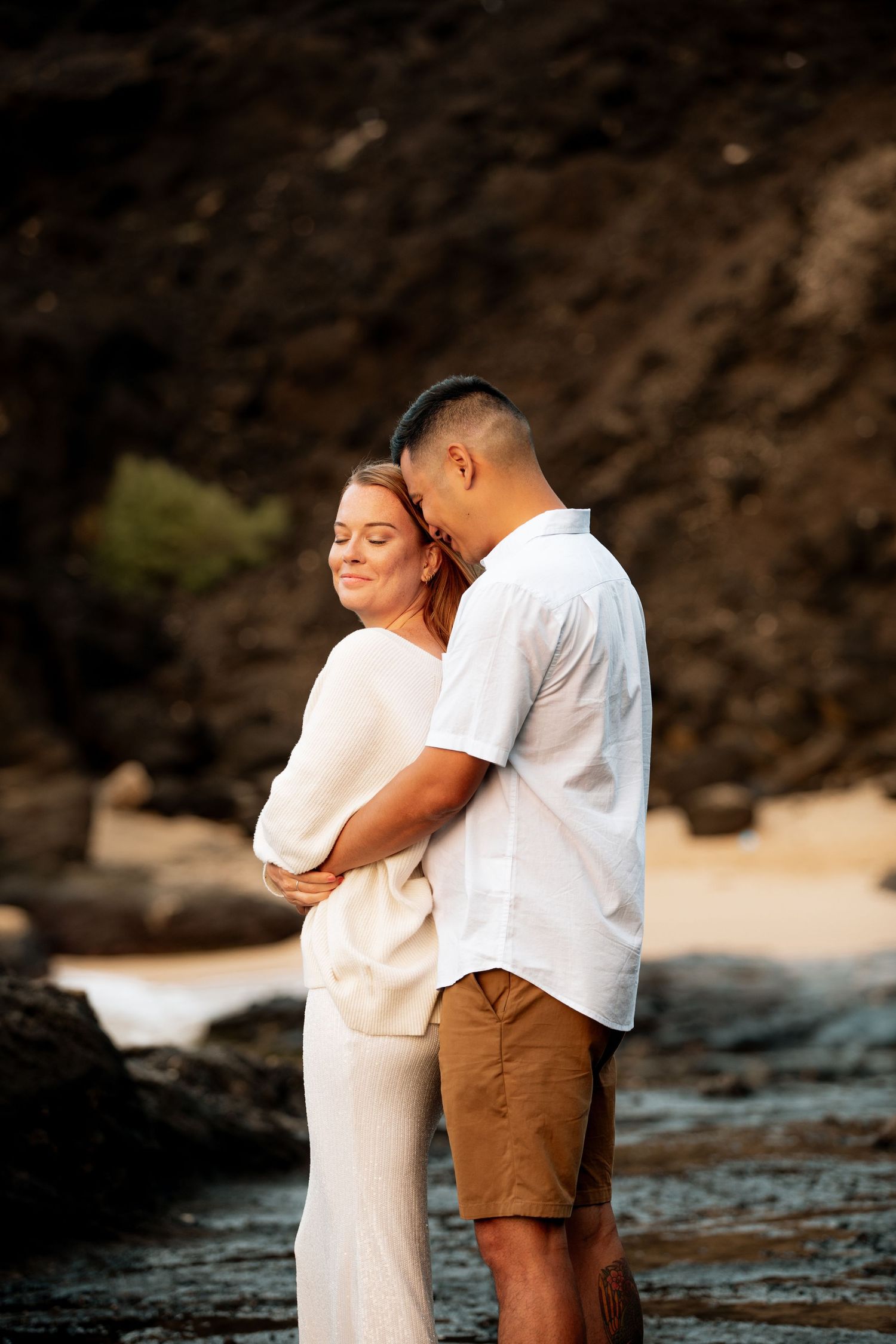 A romantic photoshoot sequence at the beach shows tender embraces between a couple in white and brown outfits.