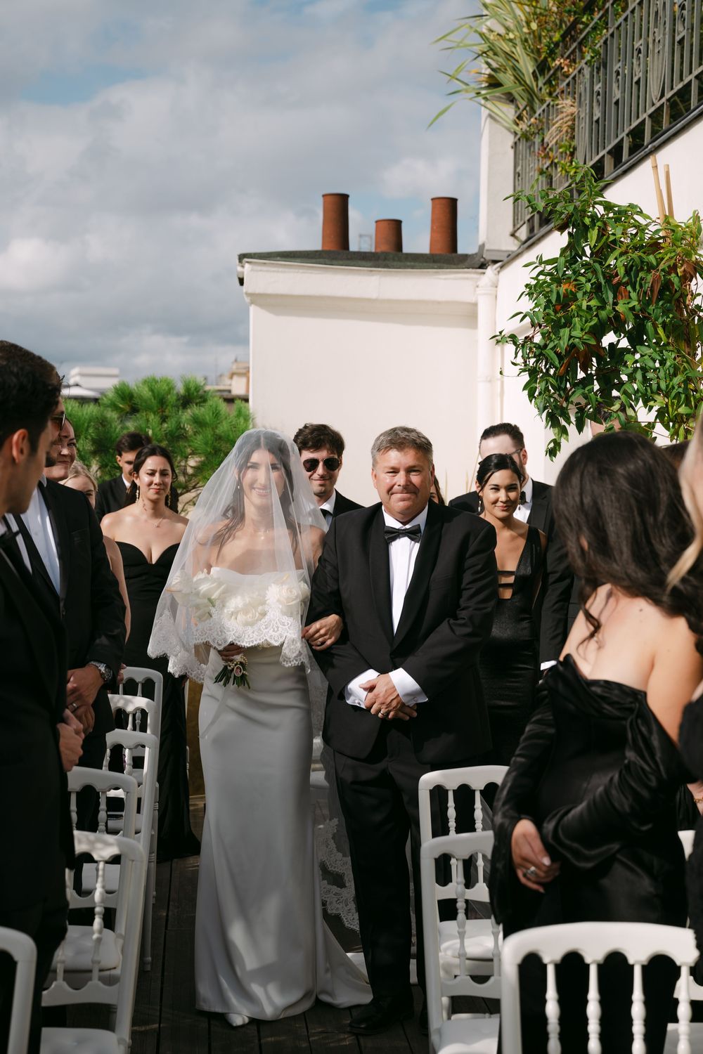 An elegant outdoor wedding ceremony on a rooftop with guests in formal attire.