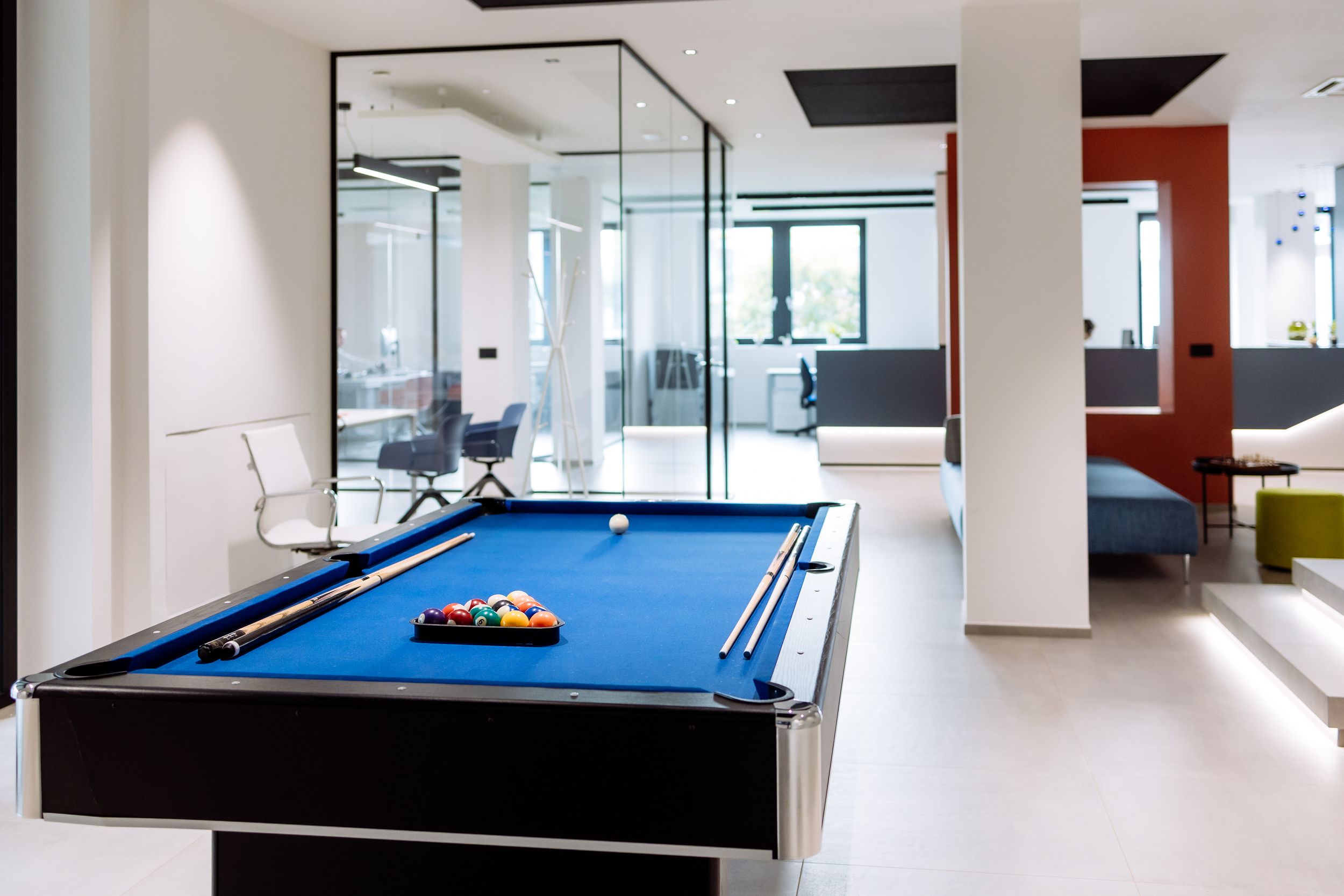 Modern game room with pool table and white minimalist design featuring sleek lighting and clean lines.