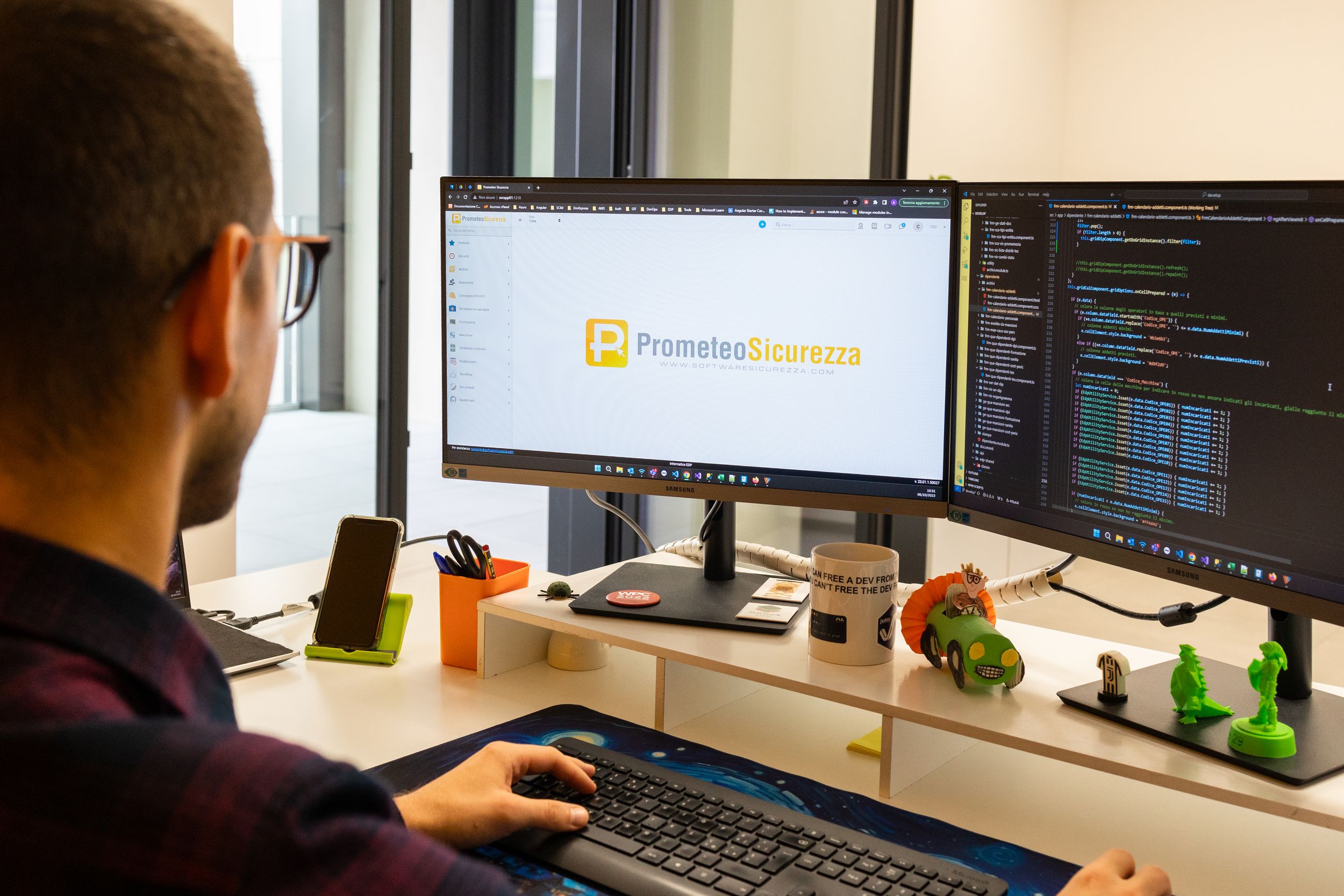 Software developer working on computer code across multiple screens in a modern office environment.