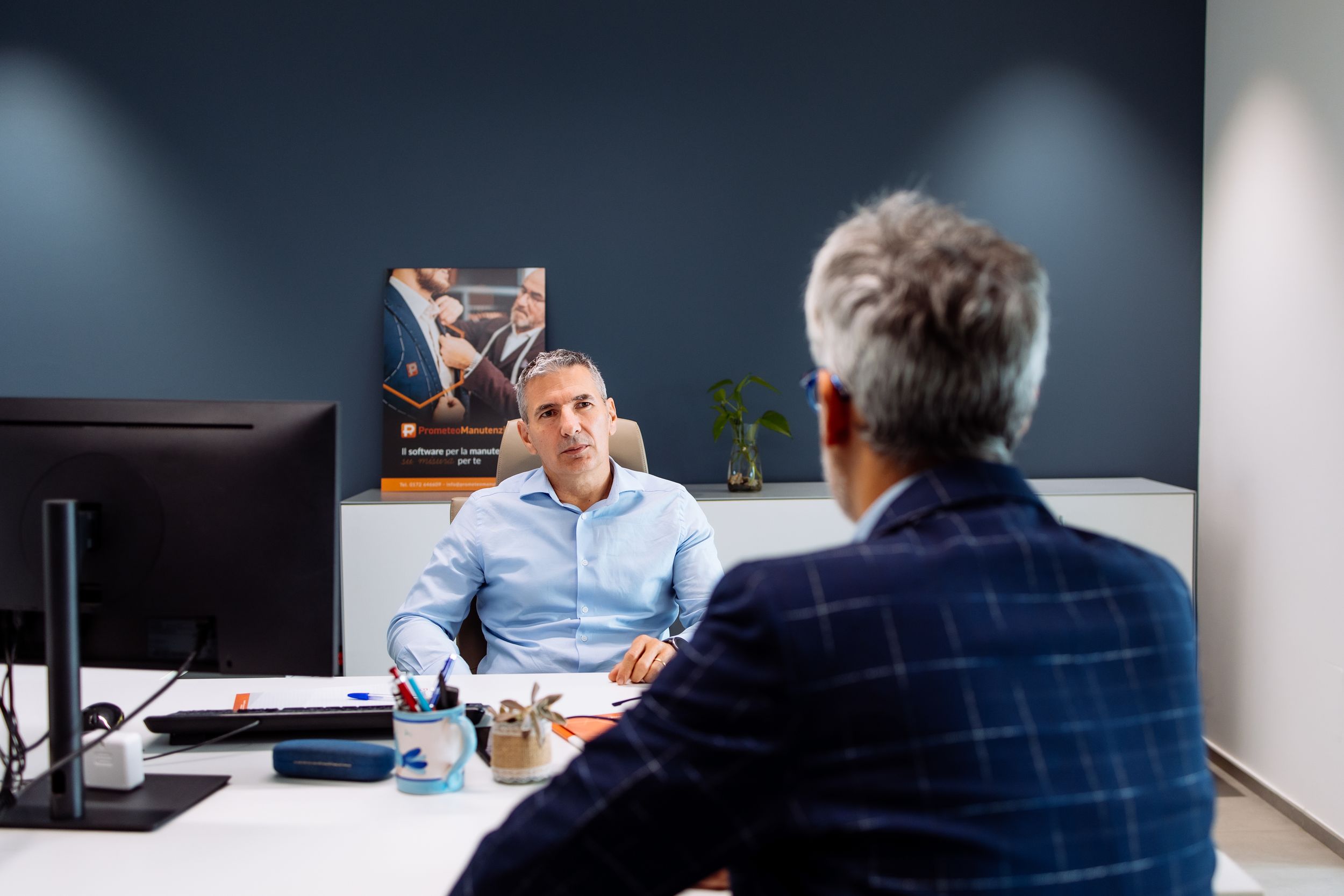 Business professionals having a meeting discussion across a desk in a modern office setting.