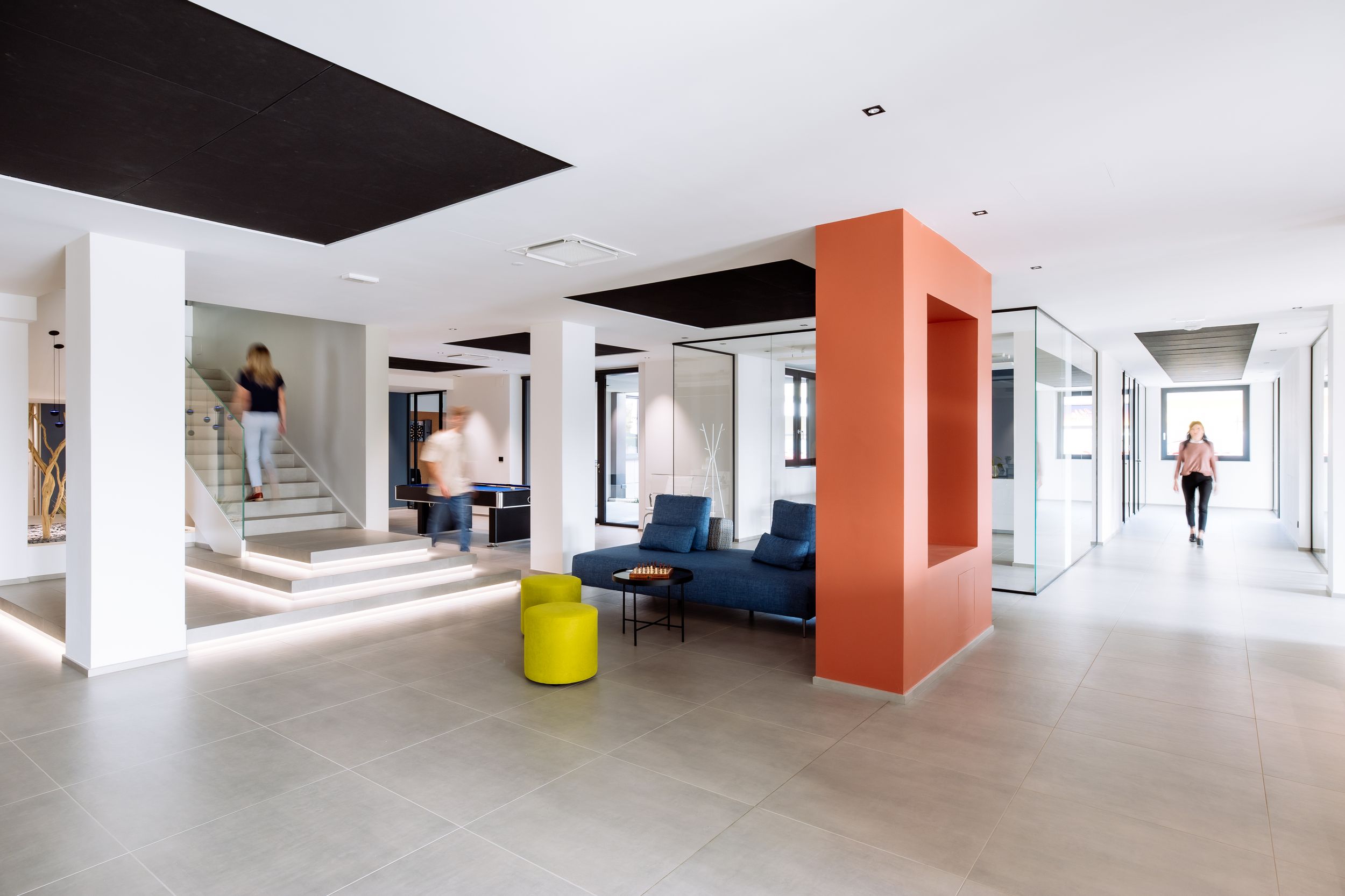 Modern office interior featuring white walls, orange accent columns, and sleek open floor plan design.