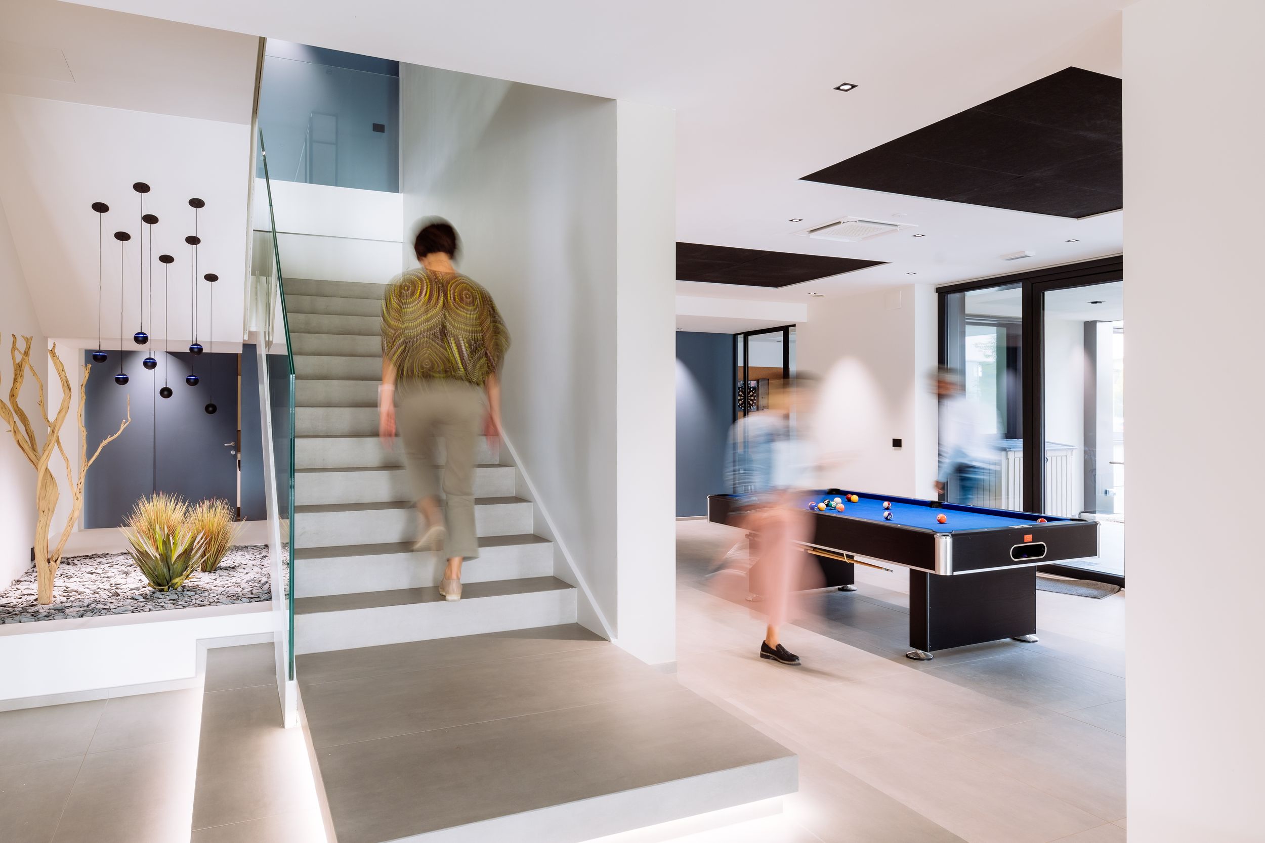 Clean minimalist interior space with glass railings, white walls and contemporary staircase design.