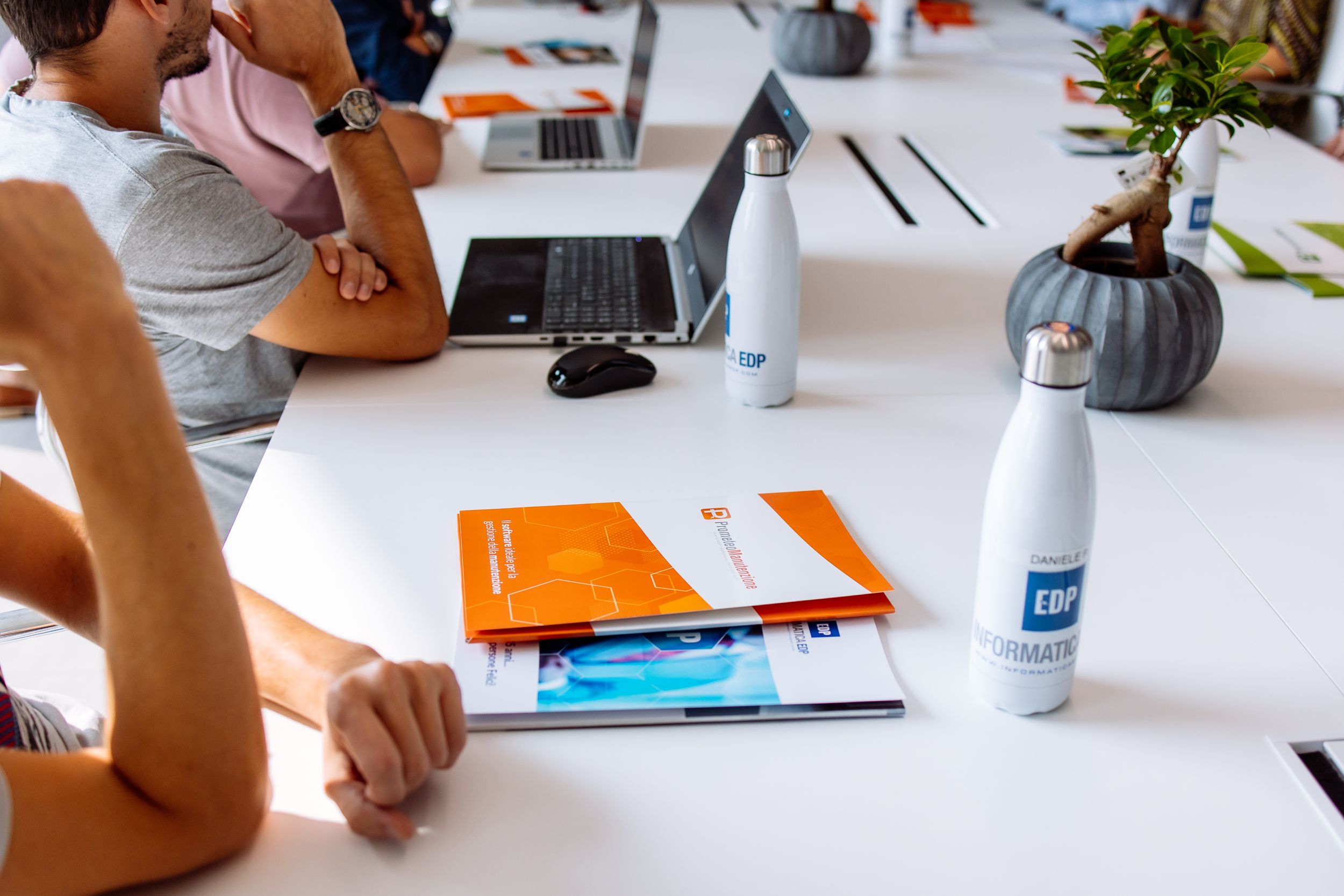 Business people collaborating at a modern conference table with laptops, notebooks and office supplies.