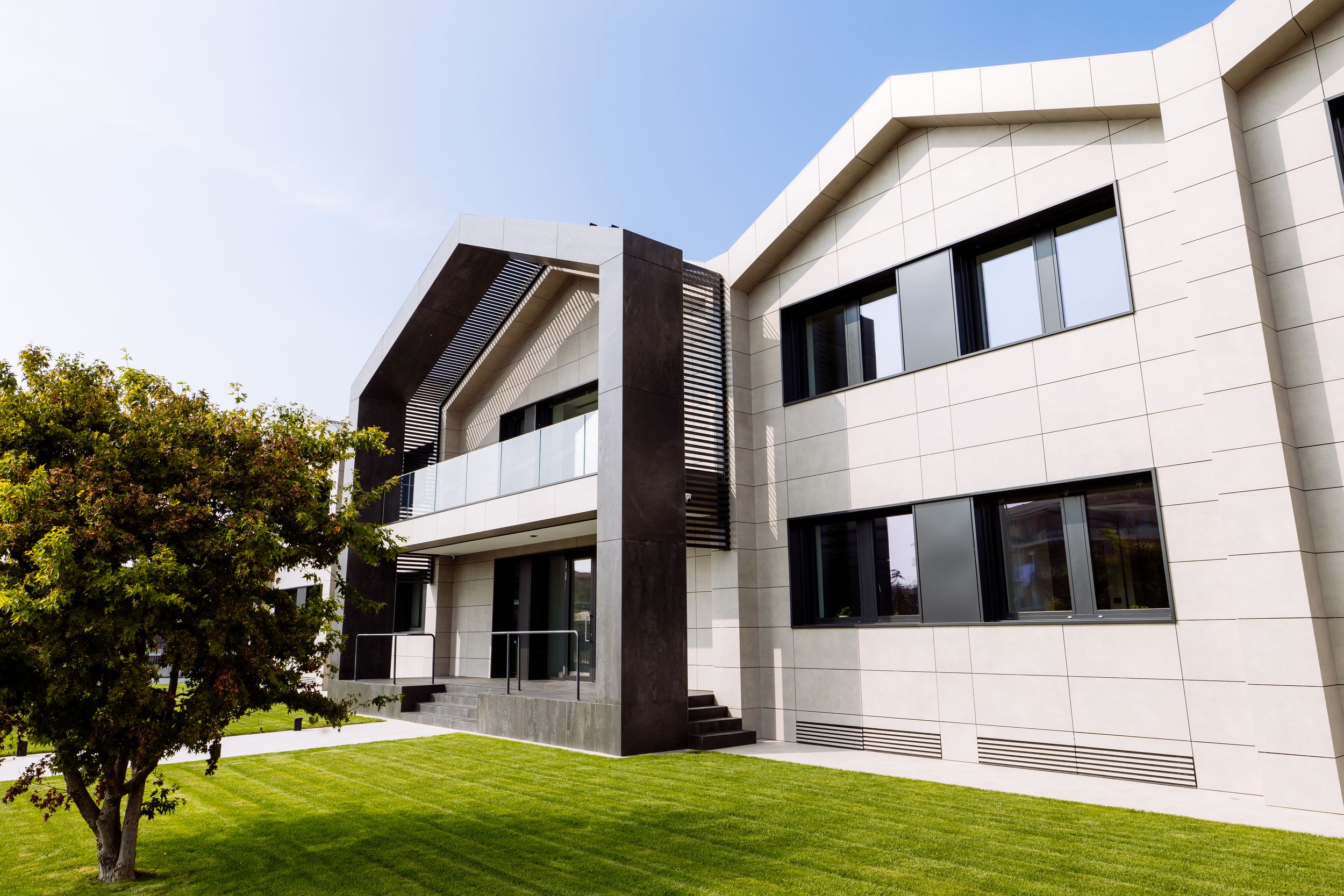 Modern luxury home exterior features geometric white stone walls and large panoramic windows.