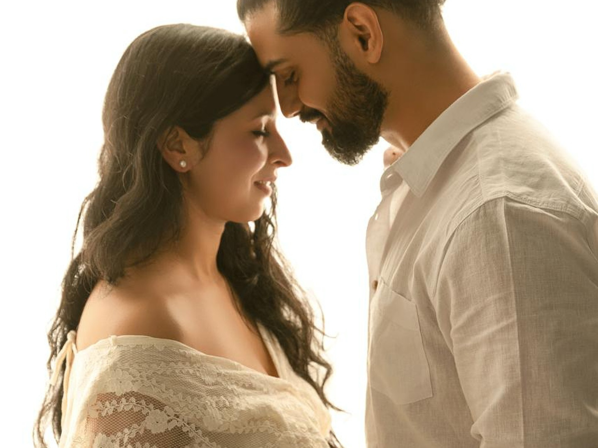 A romantic couple in wedding attire embraces in soft natural light during an intimate photography session.