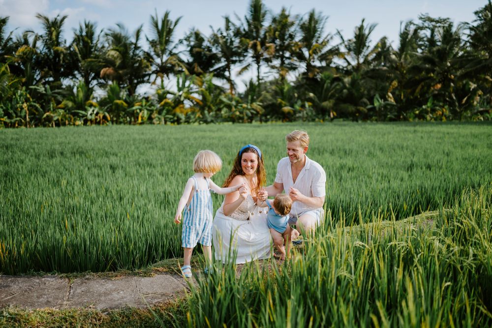 Tropical landscape photo featuring family on dirt trail through lush agricultural fields.