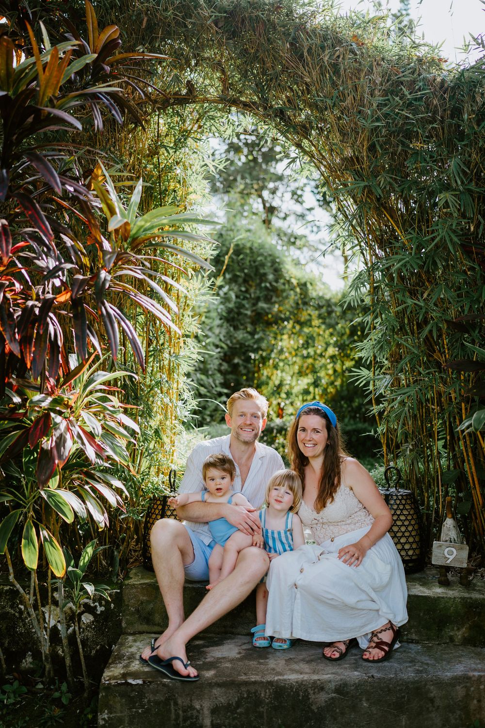 People sitting together on stone steps surrounded by tropical plants and bamboo.