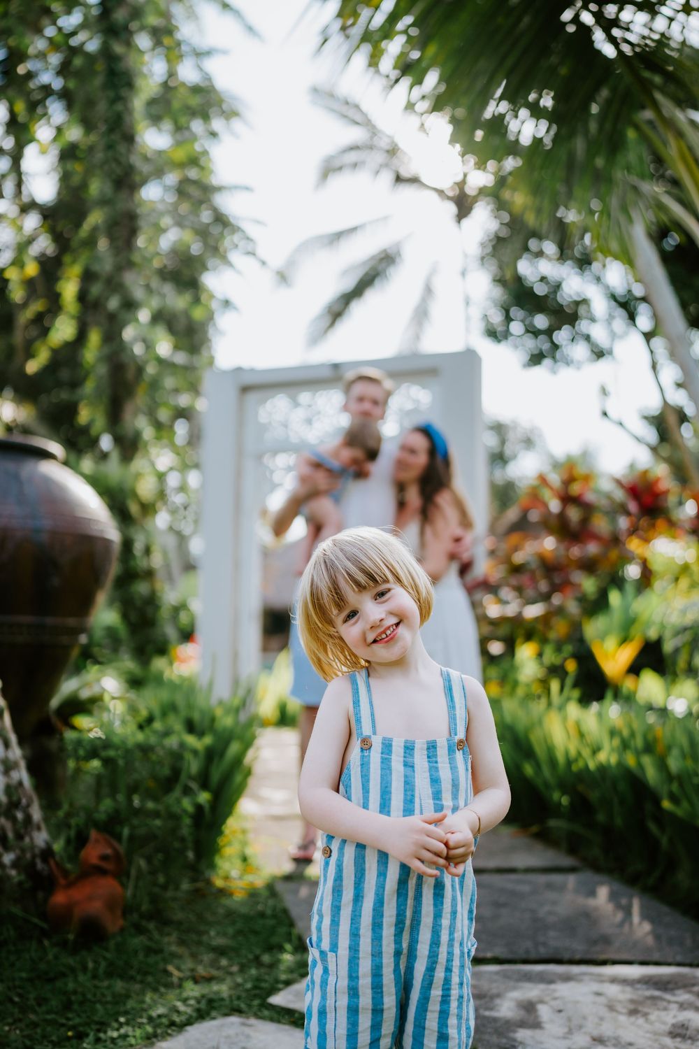 People enjoying a playful moment in a tropical garden setting with palm trees.