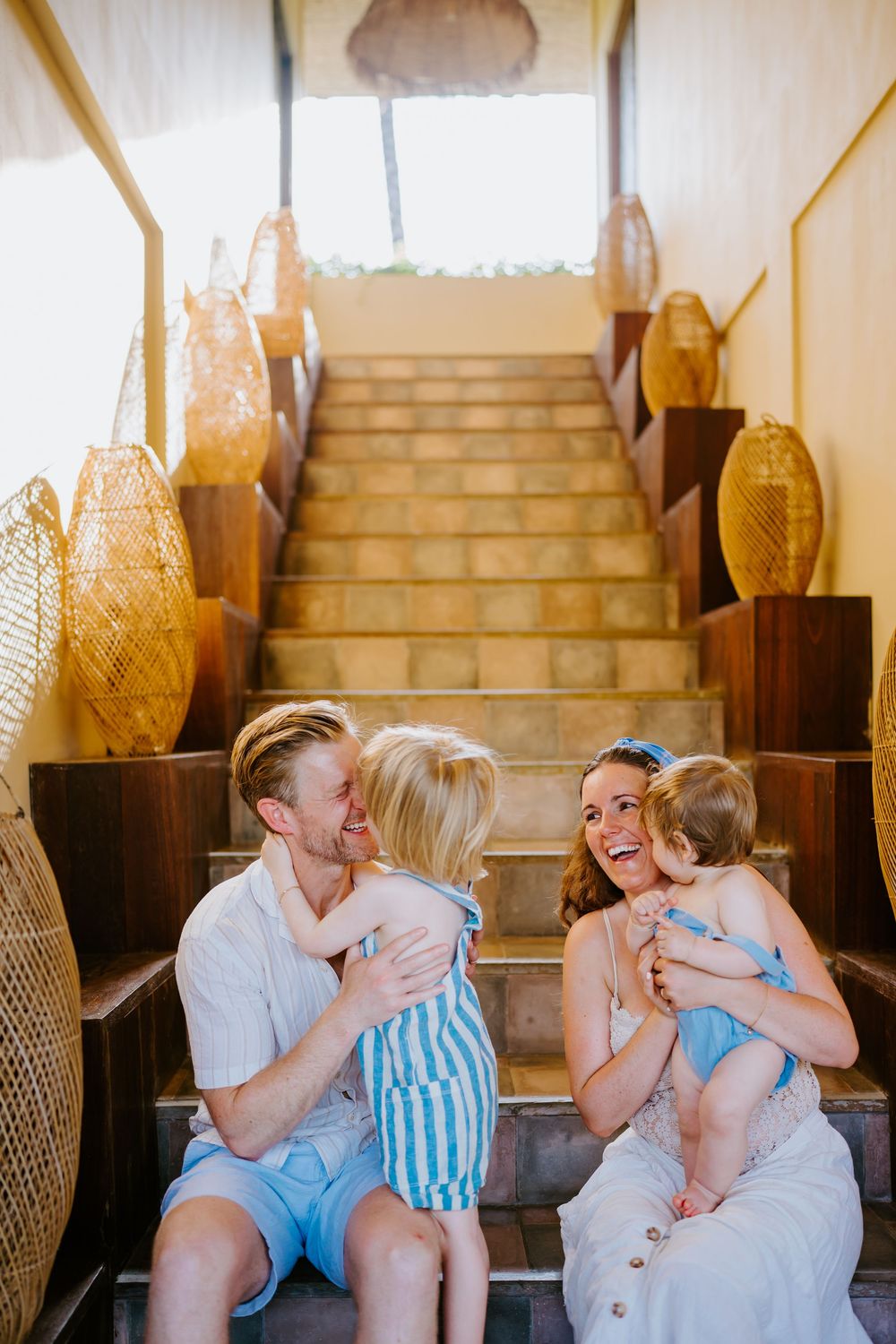 Joyful family moment captured on indoor stairs with warm lighting.