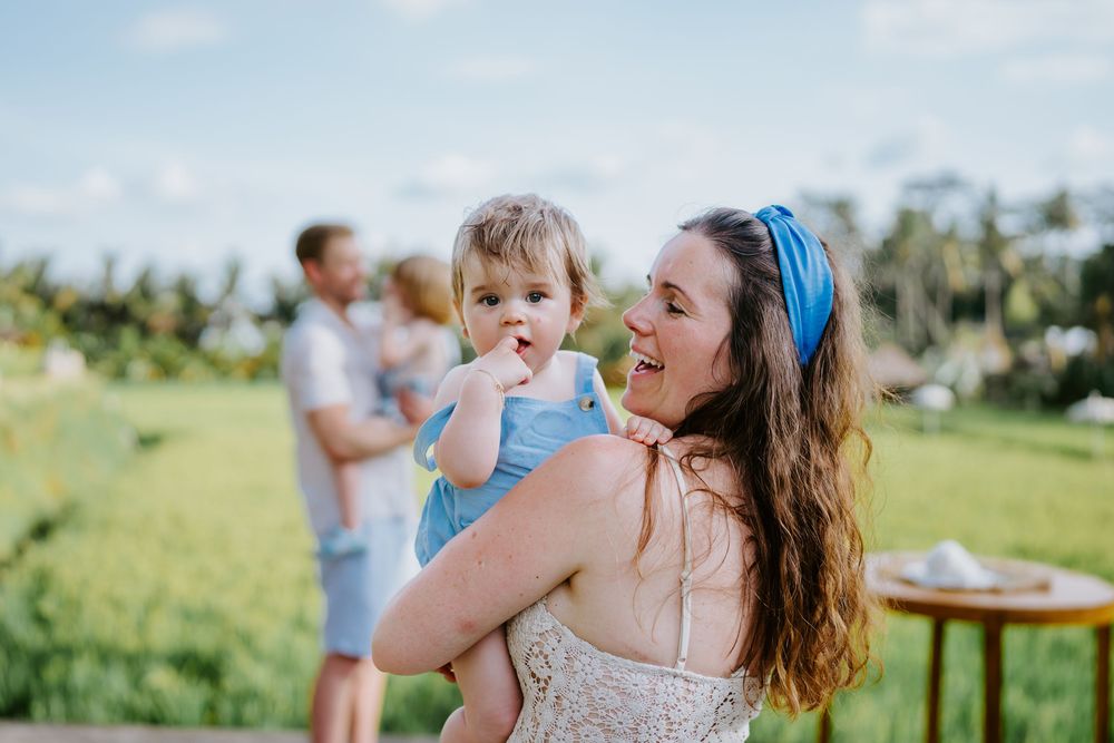 Family sharing intimate moments during an outdoor photoshoot in a tropical setting.