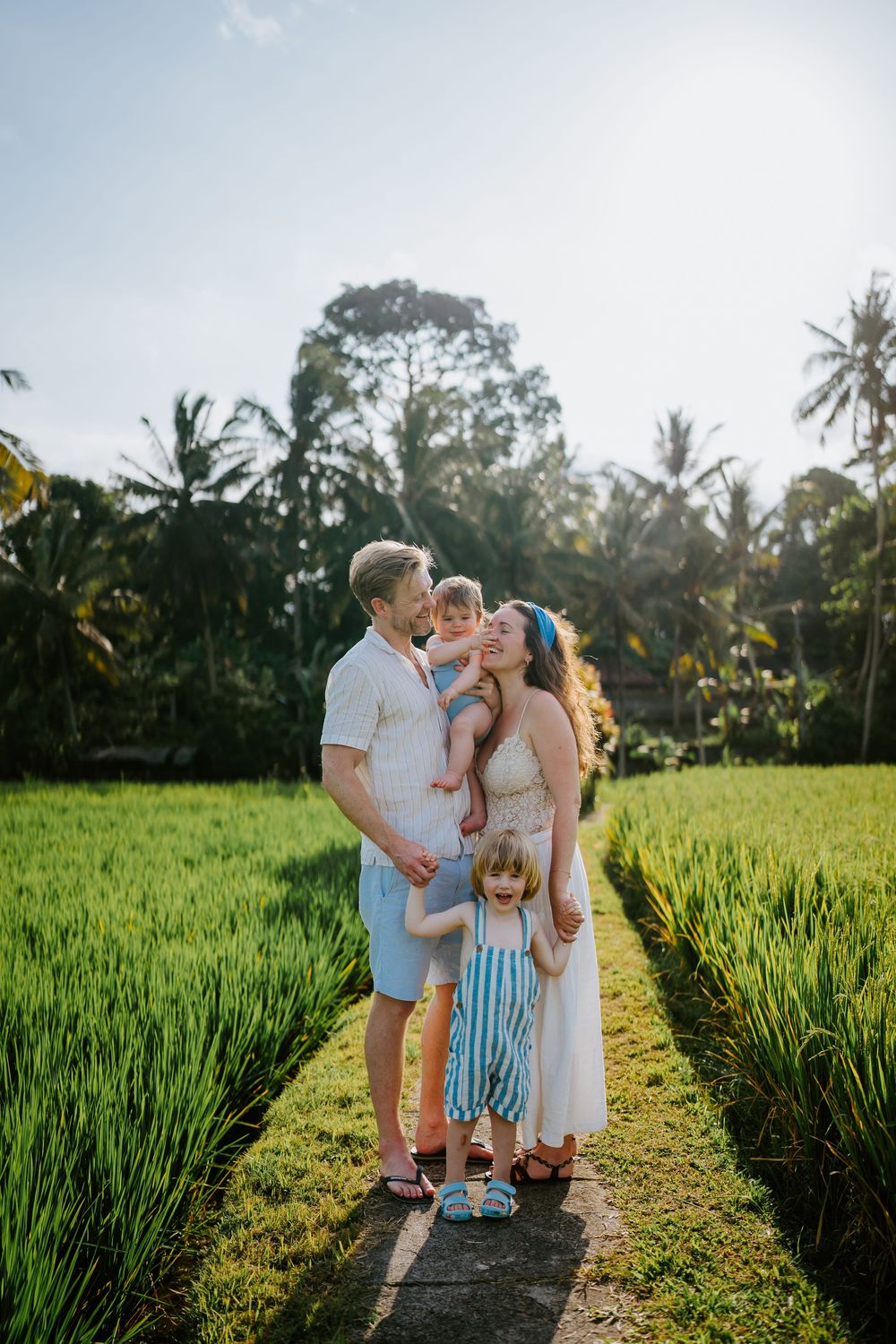 Group enjoying a sunset moment together on a rustic path between rice paddies in tropical setting.