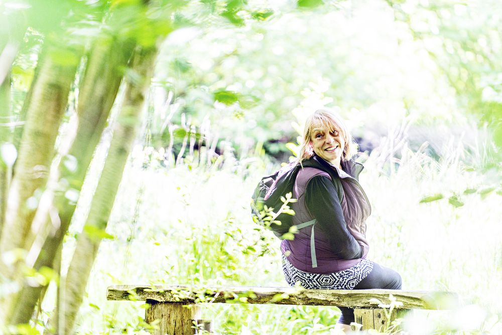 Woodland Well-being portrait for the Suffolk Wildlife Trust - A woman sitting on a bench in a sunlit woodland, Suffolk