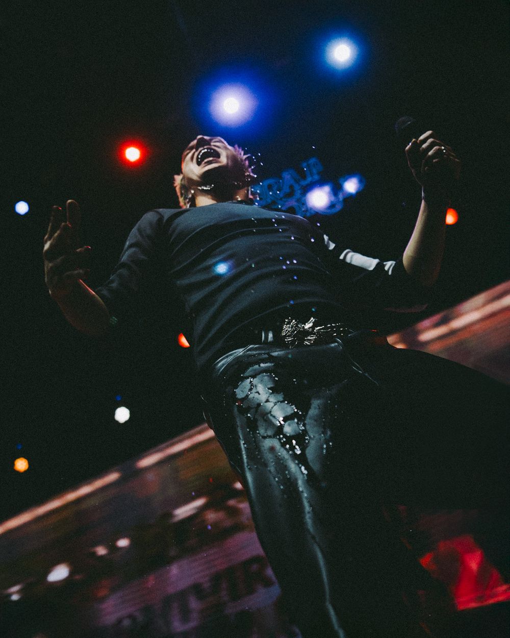 Concert performer silhouetted against dramatic blue stage lighting during an energetic live performance.