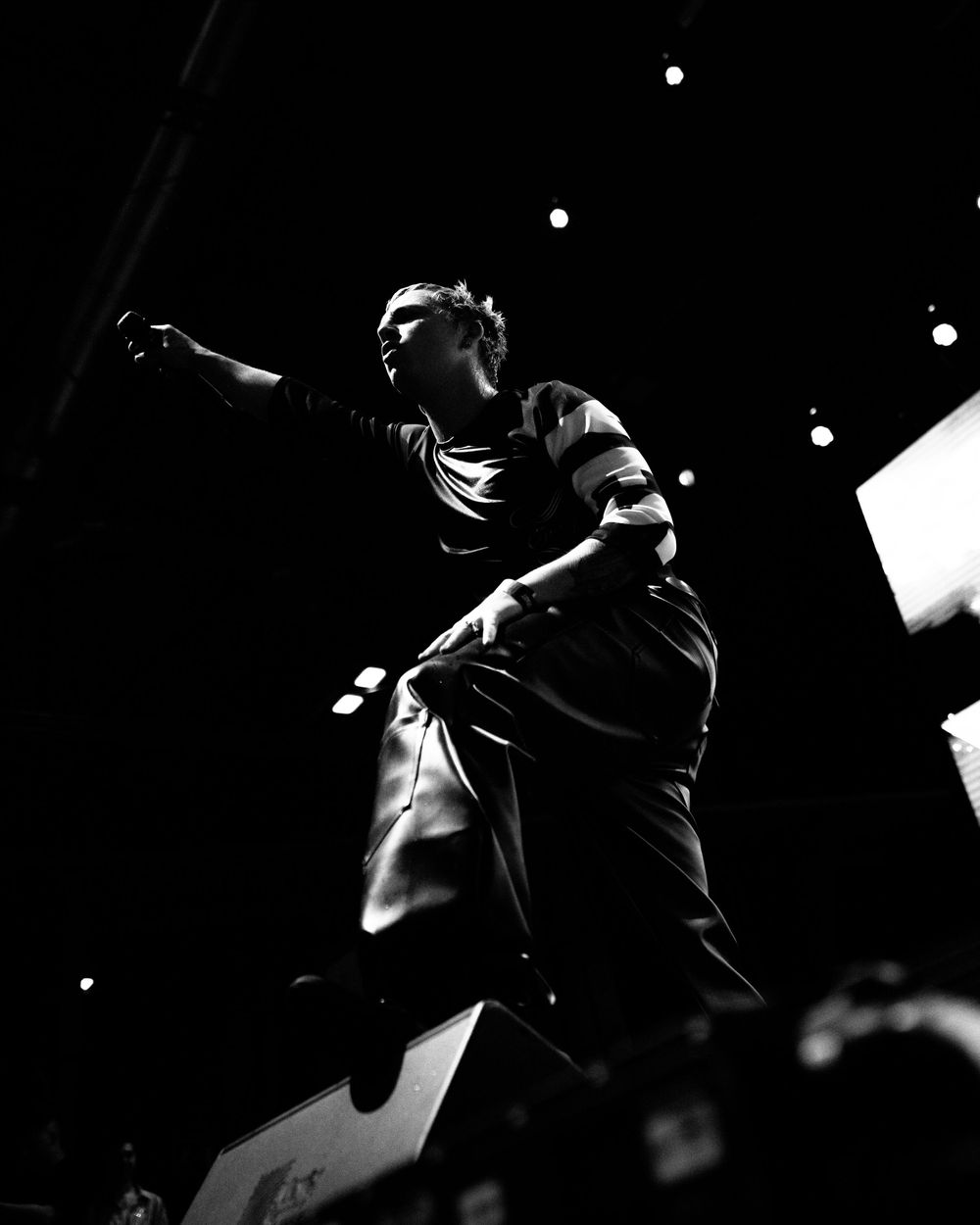 A dramatic black and white performance photo series showing silhouettes of performers on stage in dynamic poses.