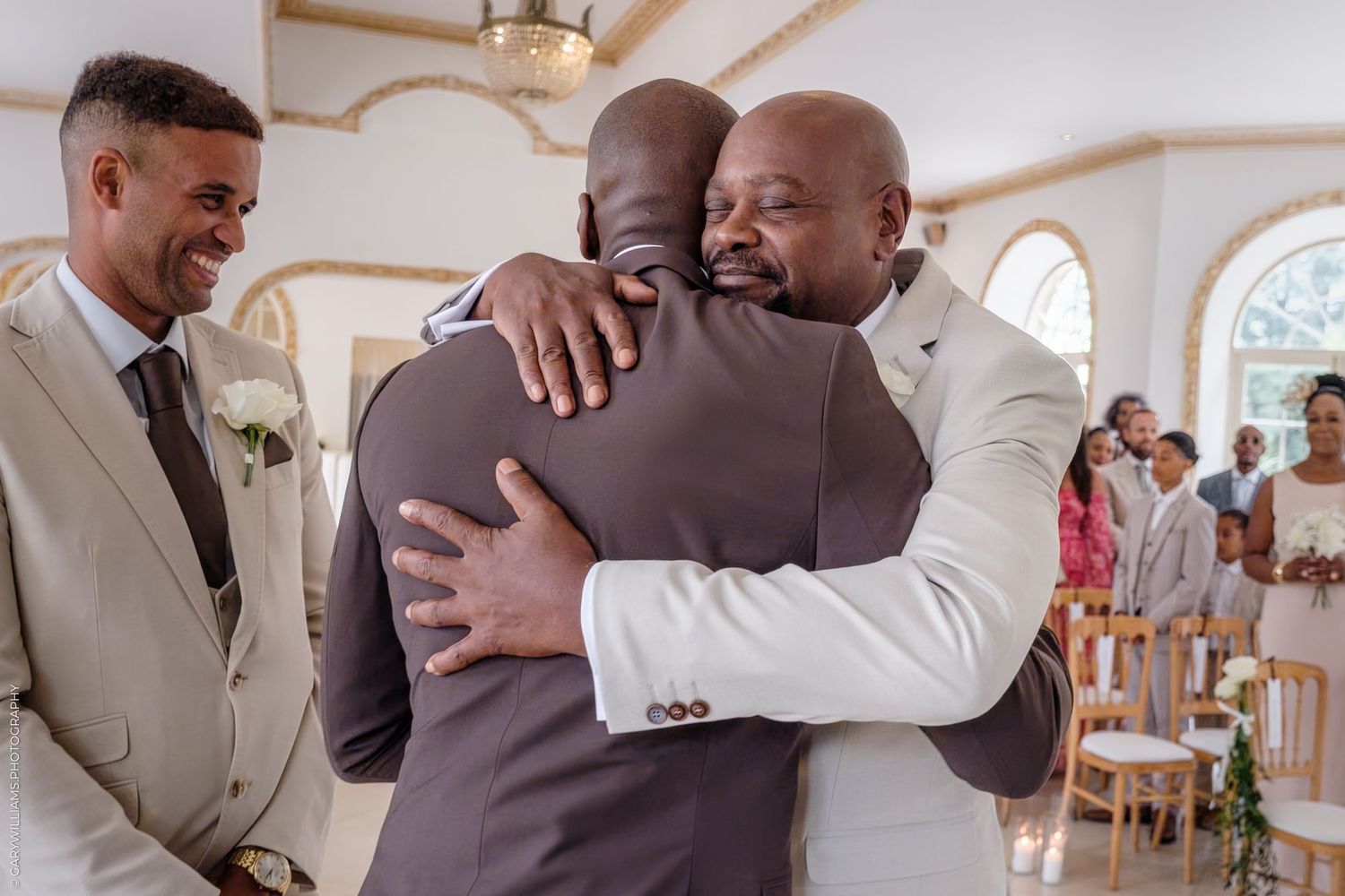 Touching moment between wedding attendees in formal attire inside an ornate white chapel setting.