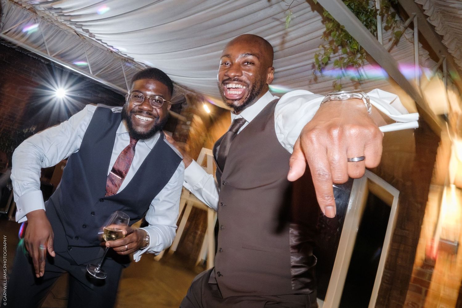 People celebrate and laugh together at a wedding reception with warm lighting and festive atmosphere.