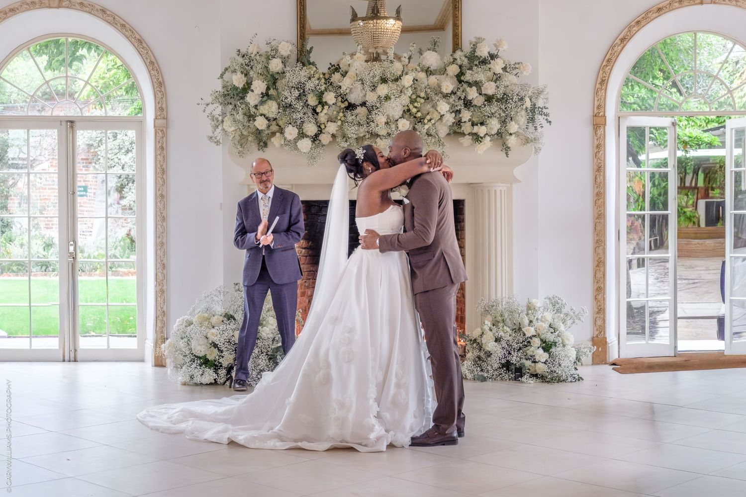 Wedding venue decorated with white floral arrangements and natural light streaming through arched windows.