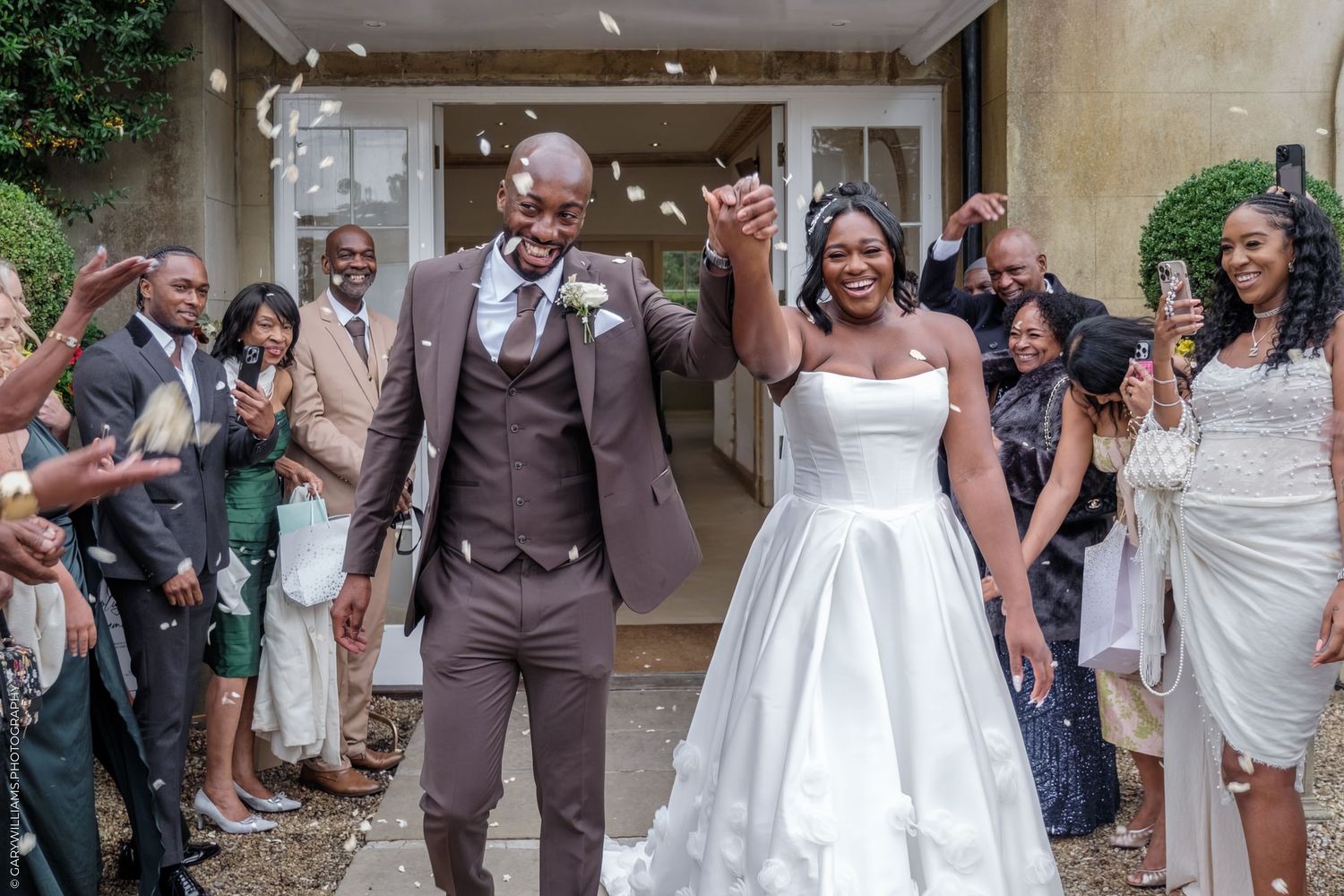 Wedding guests celebrate and throw confetti at a joyful outdoor celebration.