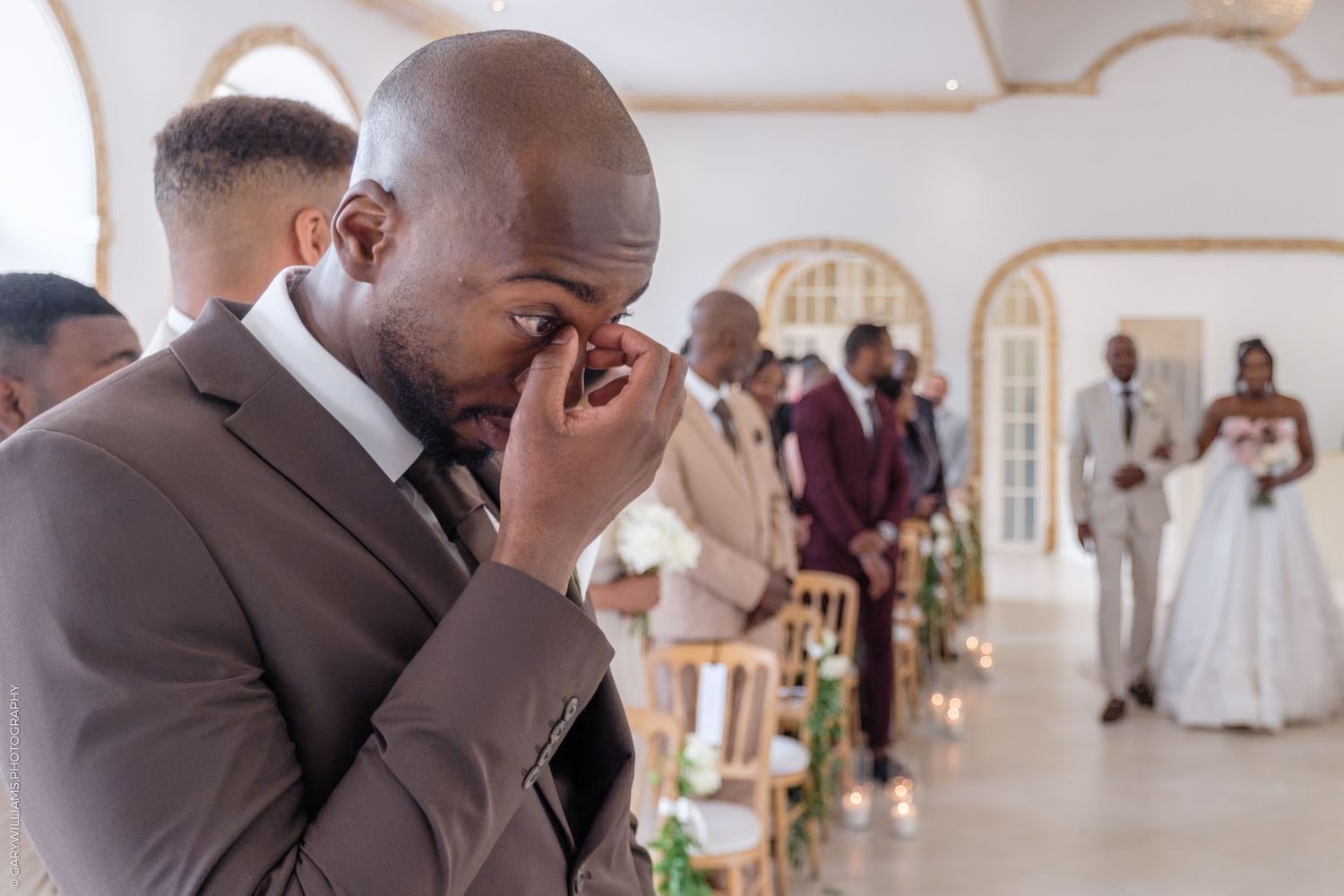 Emotional wedding moment captured in an elegant white chapel with arched windows and decorative details.