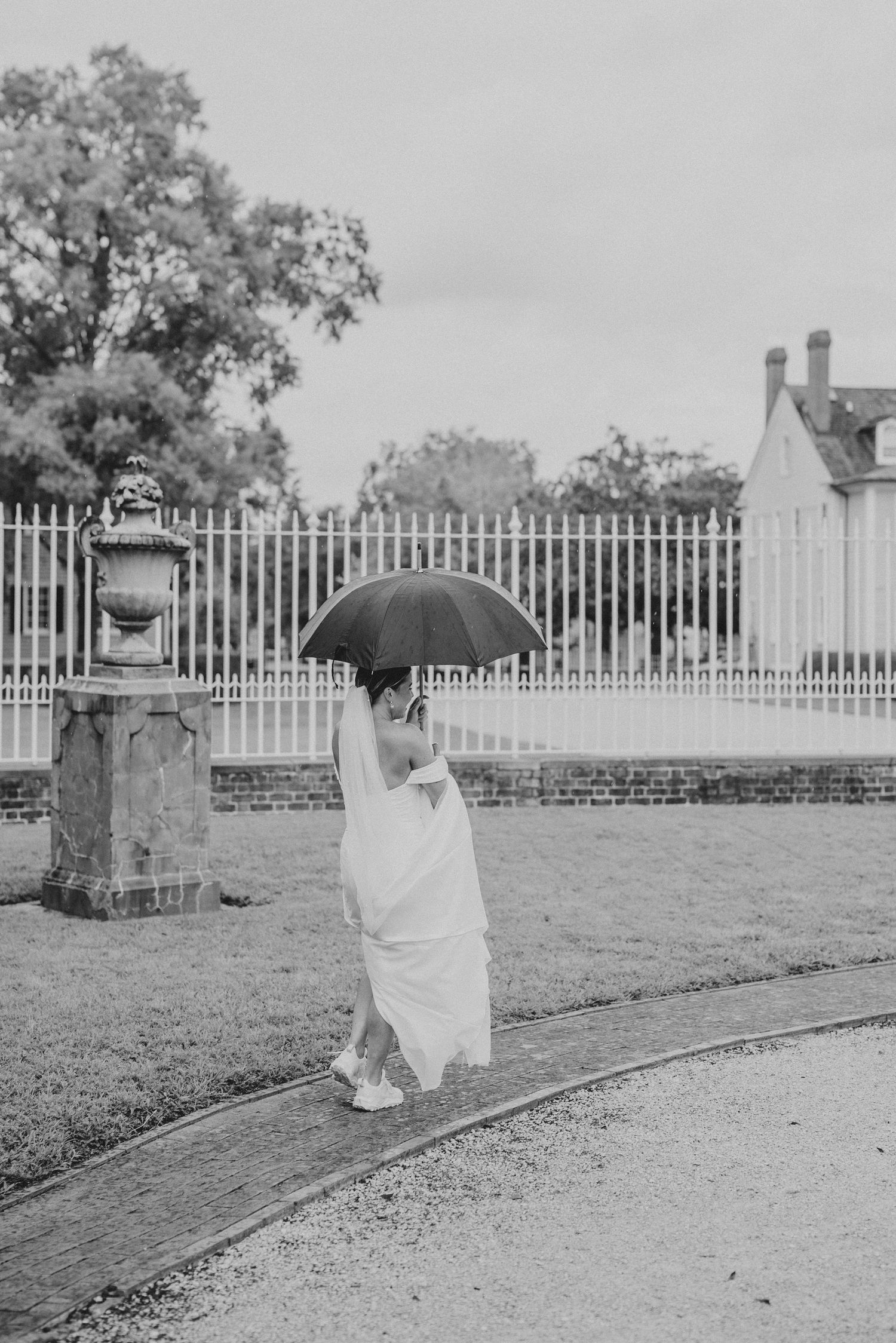 A black and white photo series showing a ghostly figure with an umbrella walking along a path by a fence.