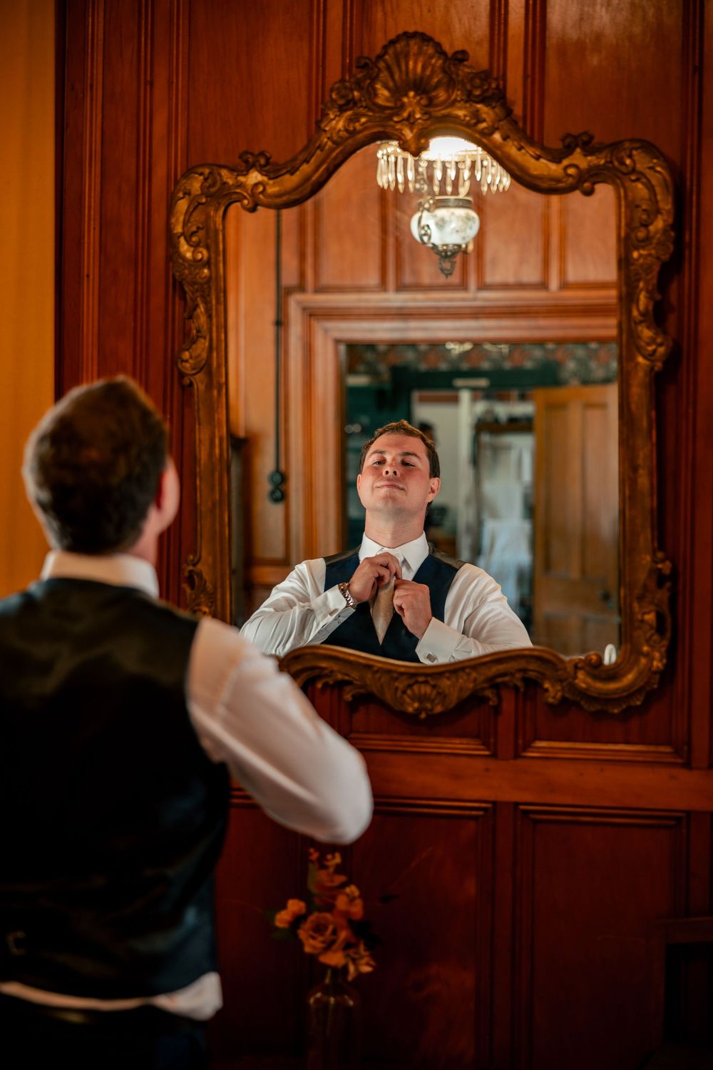 A bartender in a wood-paneled room pours drinks at an elegant venue with ornate mirrors and decor.