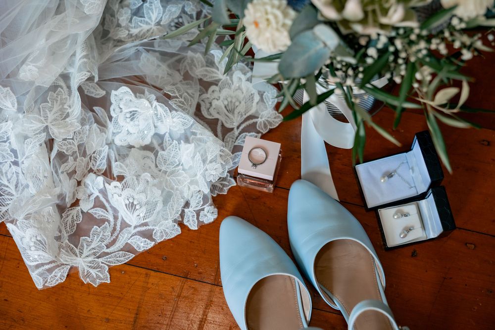 White wedding shoes and delicate lace details arranged on a wooden surface for bridal preparation.