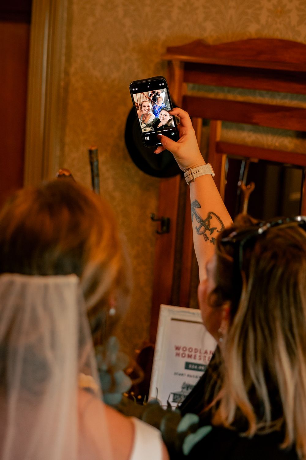 Person taking a selfie photo with a mobile phone in an indoor setting with warm lighting.