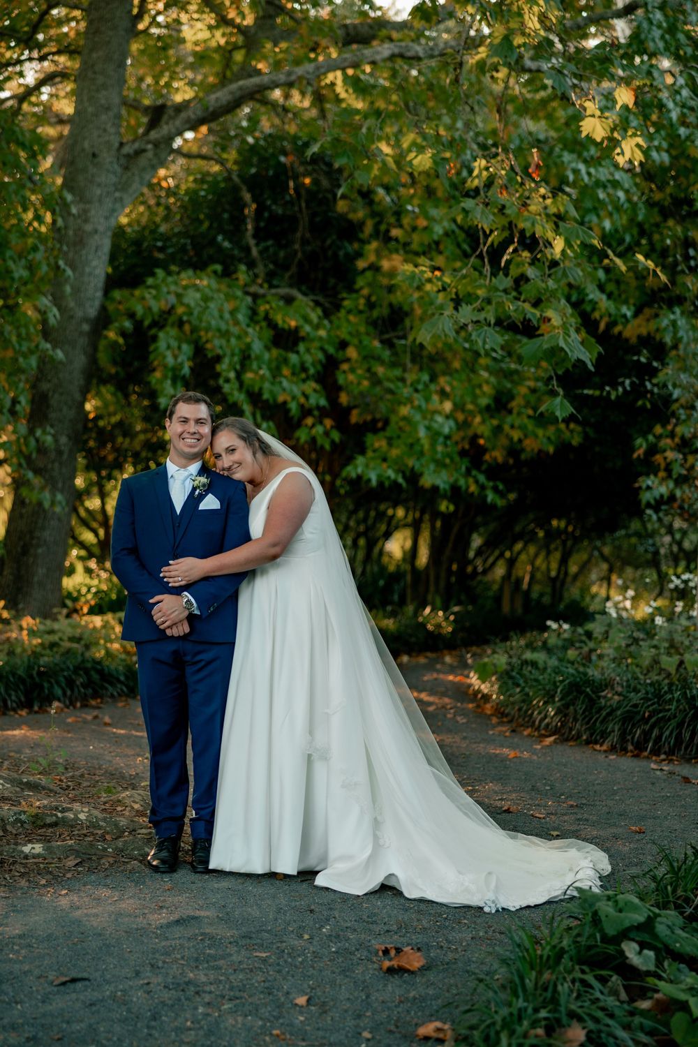 A romantic outdoor wedding photo session with a couple posing together in a wooded setting at golden hour.